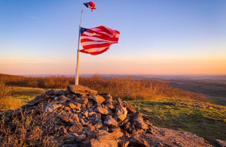 american flag on mountain summit at sunset