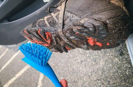 blue plastic brush cleaning dirt off bottom of dirty hiking hoot