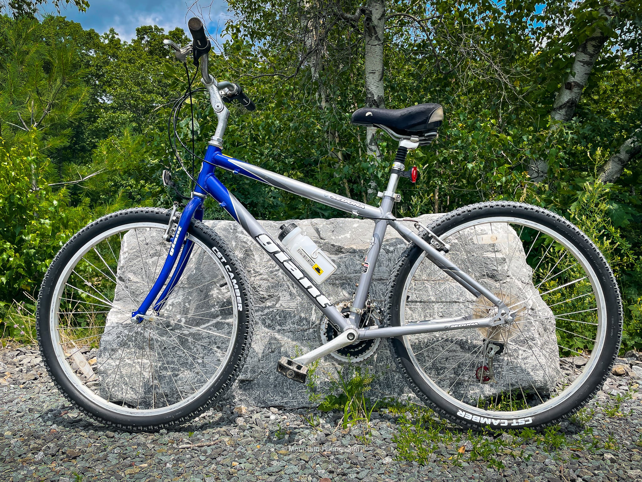 blue and silver mountain bike leaning against boulder