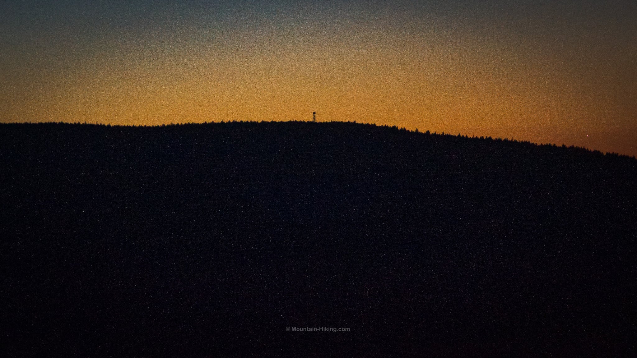 silhouette of fire tower on summit at dusk