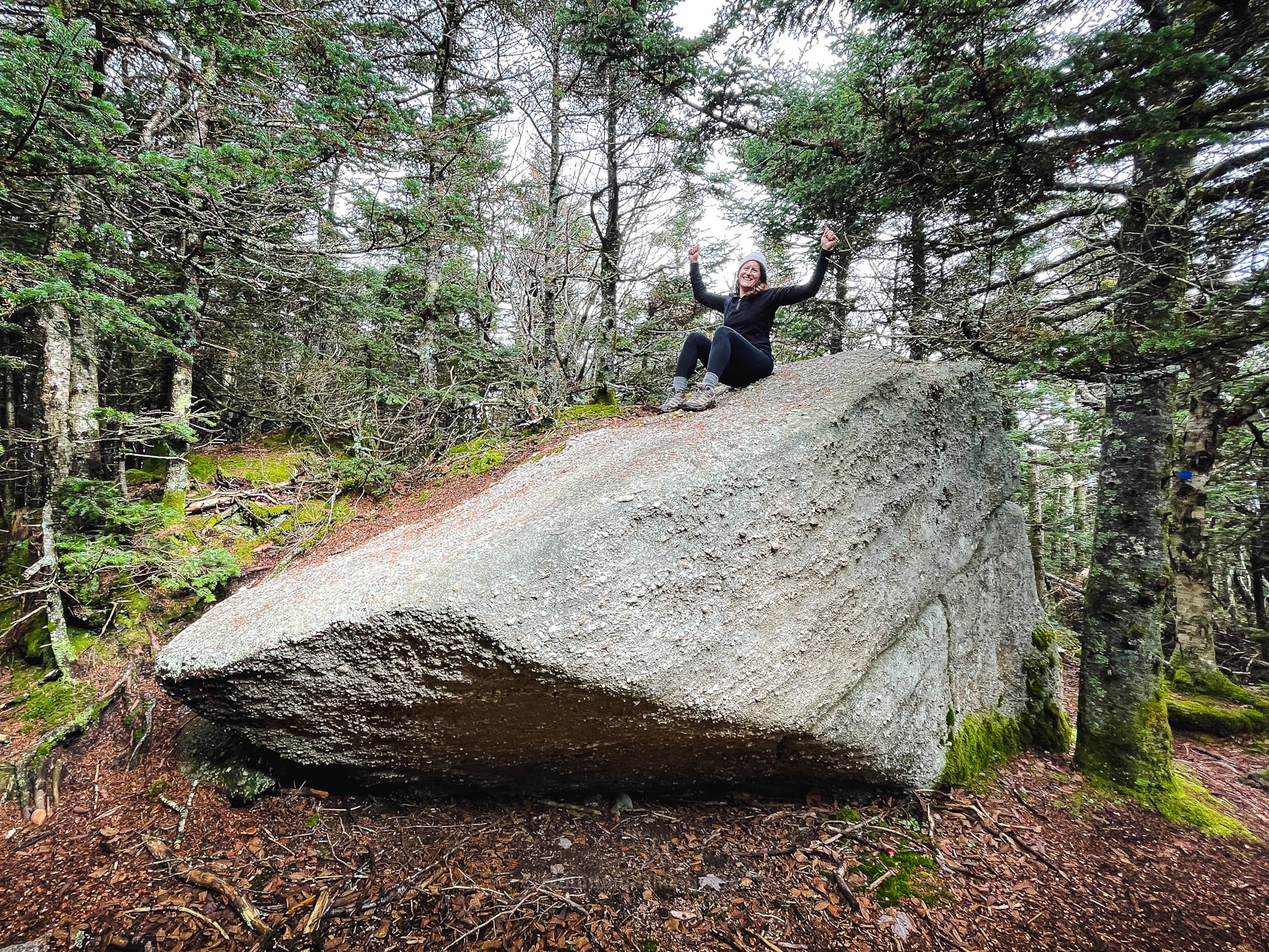 hiker sitting on erratic boulder
