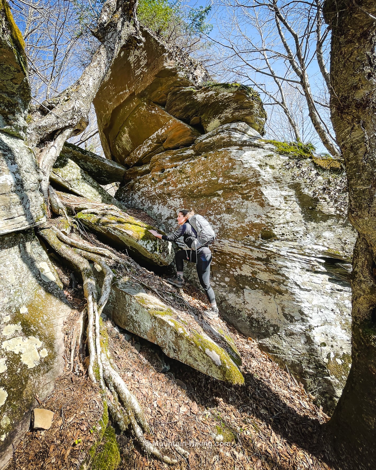 hiker climbing between large jagged boulders