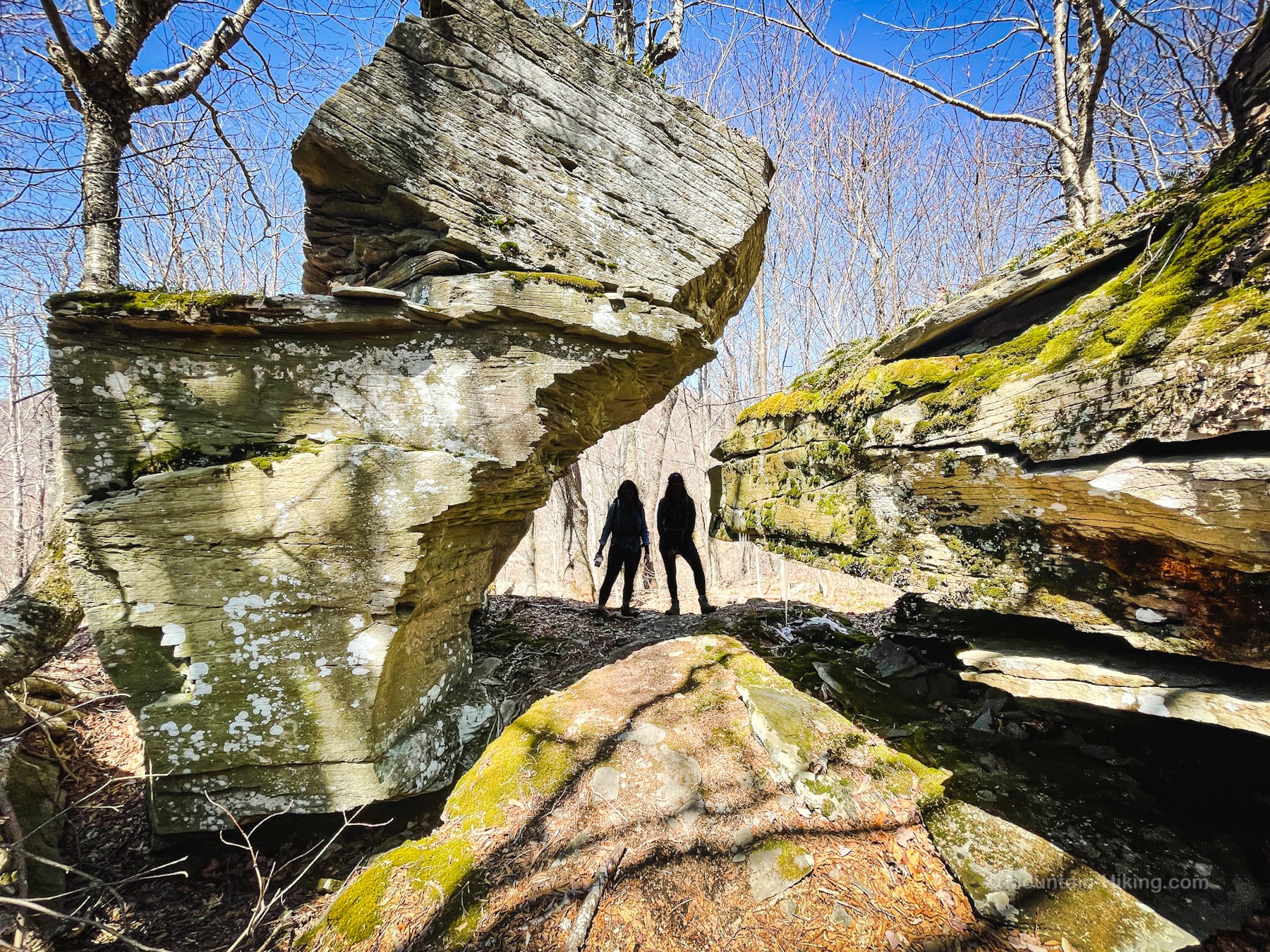 two hikers in silhouette in a rock chasm
