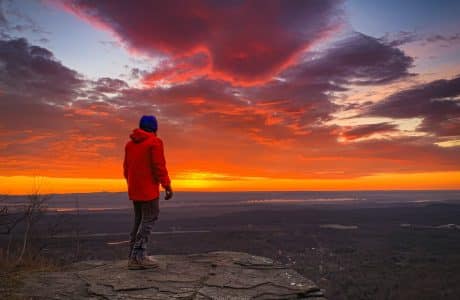 hiker faces east for sunrise
